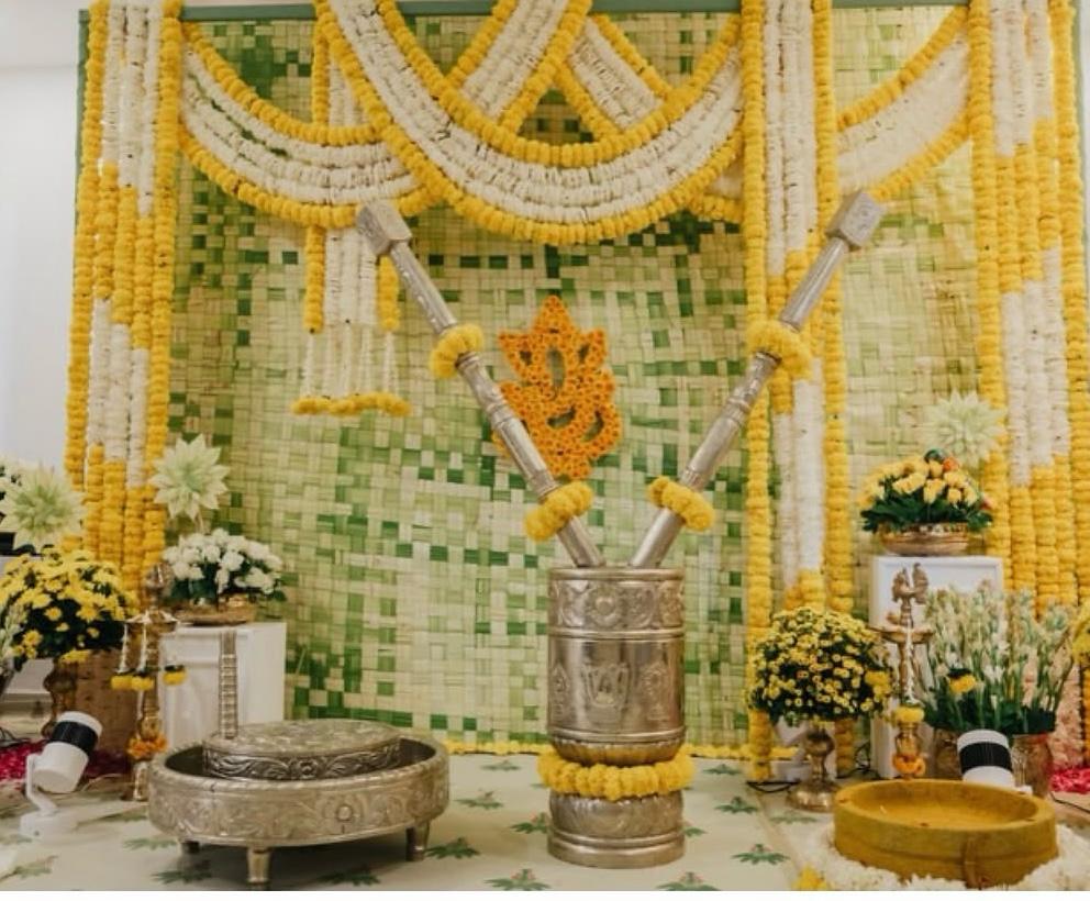 Intimate home pooja and housewarming setup with brass pestle, mortar, and floral grinding stones